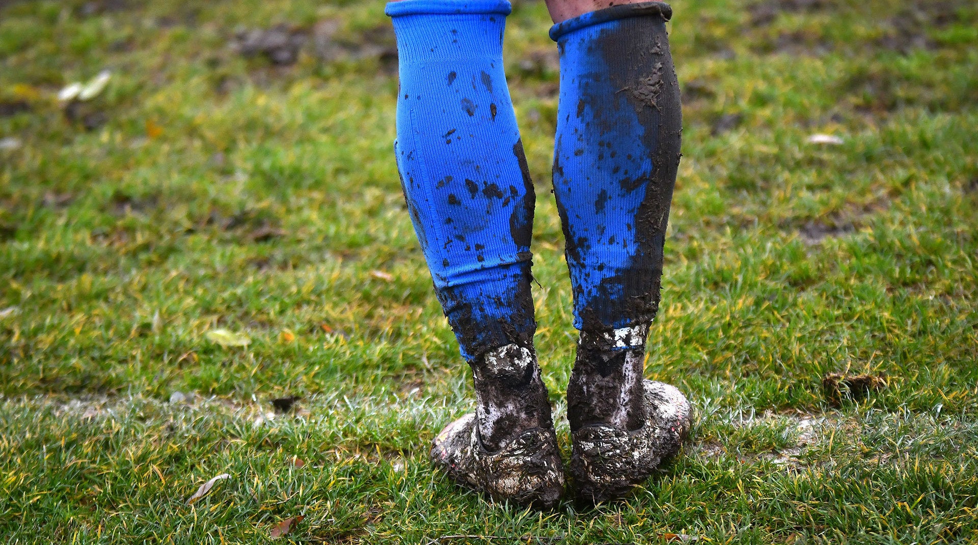 Muddy boots and leggings on a grassy field