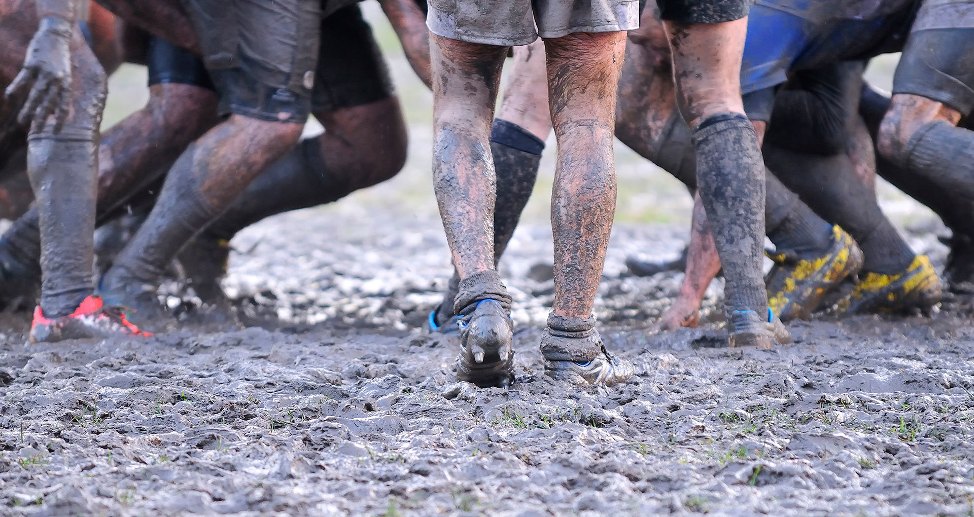 Muddy legs of people participating in a muddy event or race.
