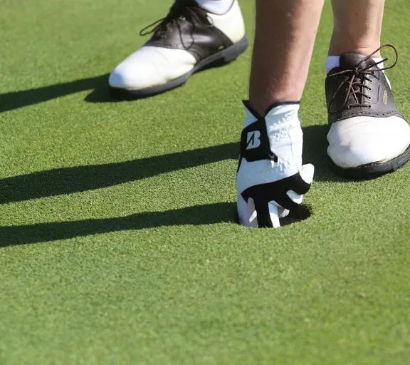Golf shoes and a glove on a green grass surface