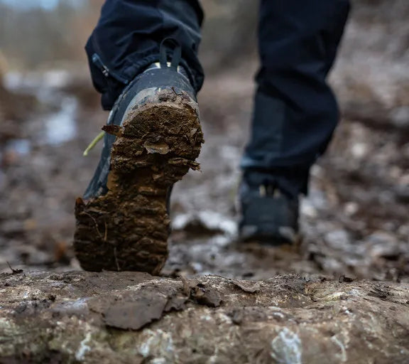 Person wearing hiking boots on a muddy trail