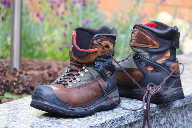 Pair of worn hiking boots on a stone surface with a blurred natural background