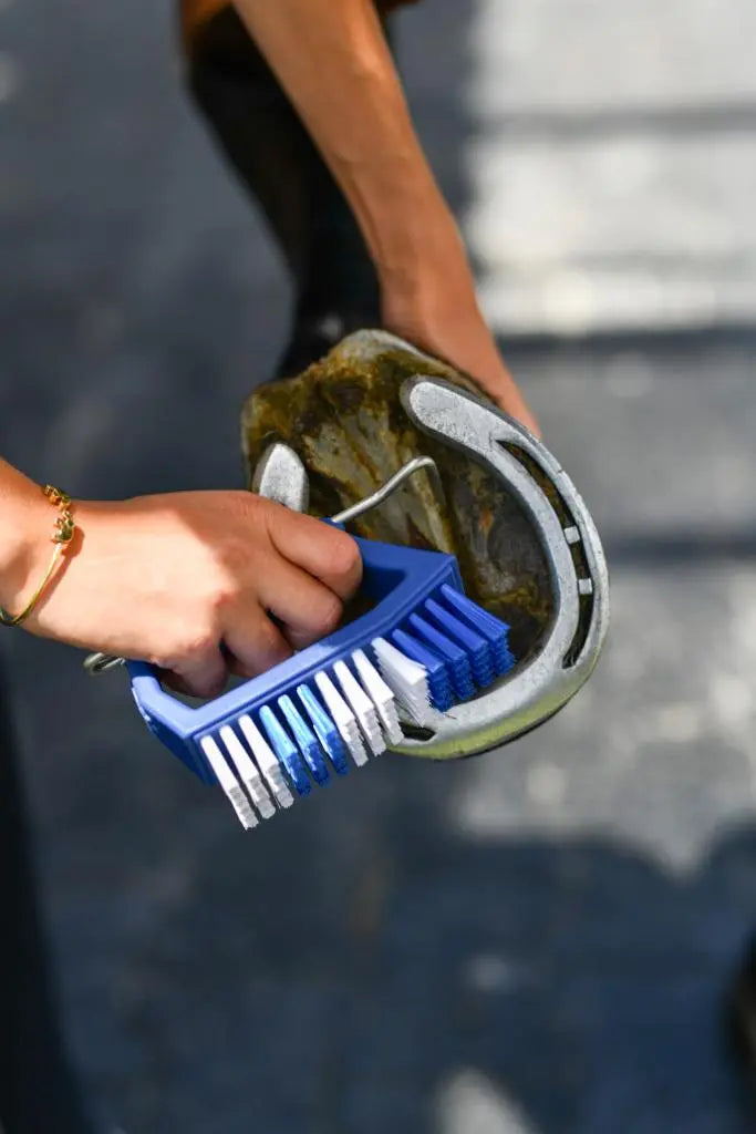 Person cleaning a horseshoe with a Kelcies Pickbrush  