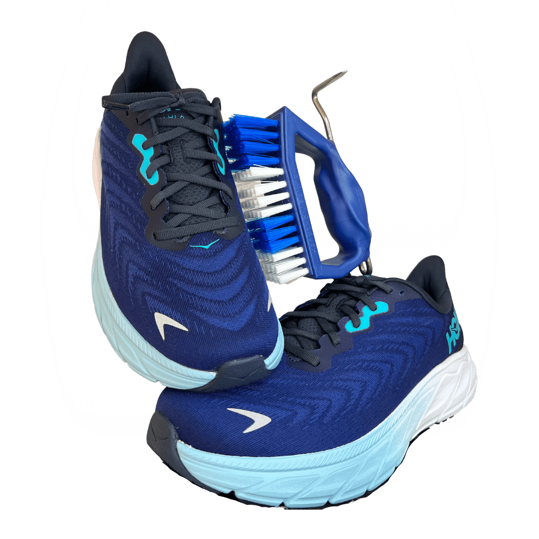 Blue and black athletic shoes with a cleaning brush on a white background